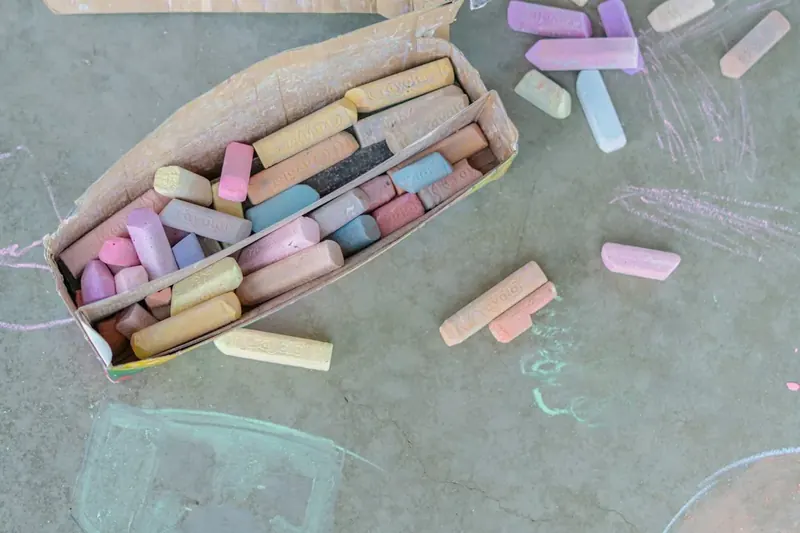 A box of soft pastel sidewalk chalk with a few loose pieces beside it.