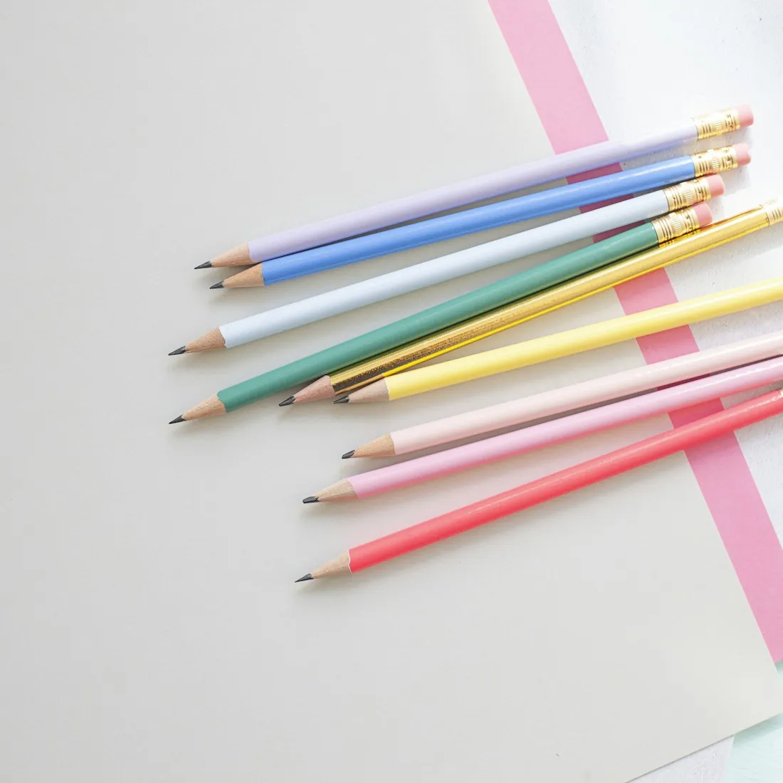 Pastel colored pencils fanned out on a sheet of pale paper.