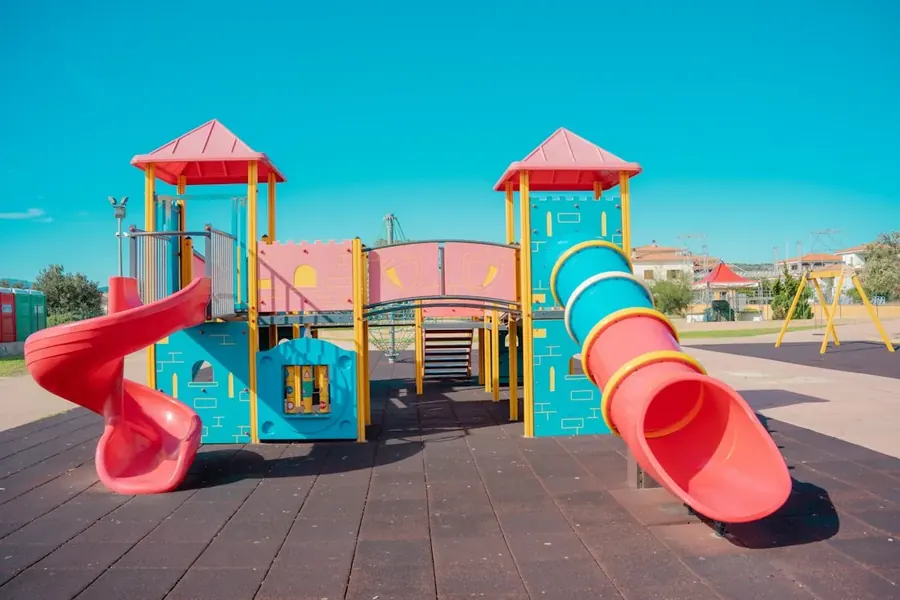 A colorful playground with slides and climbing towers under a clear blue sky.